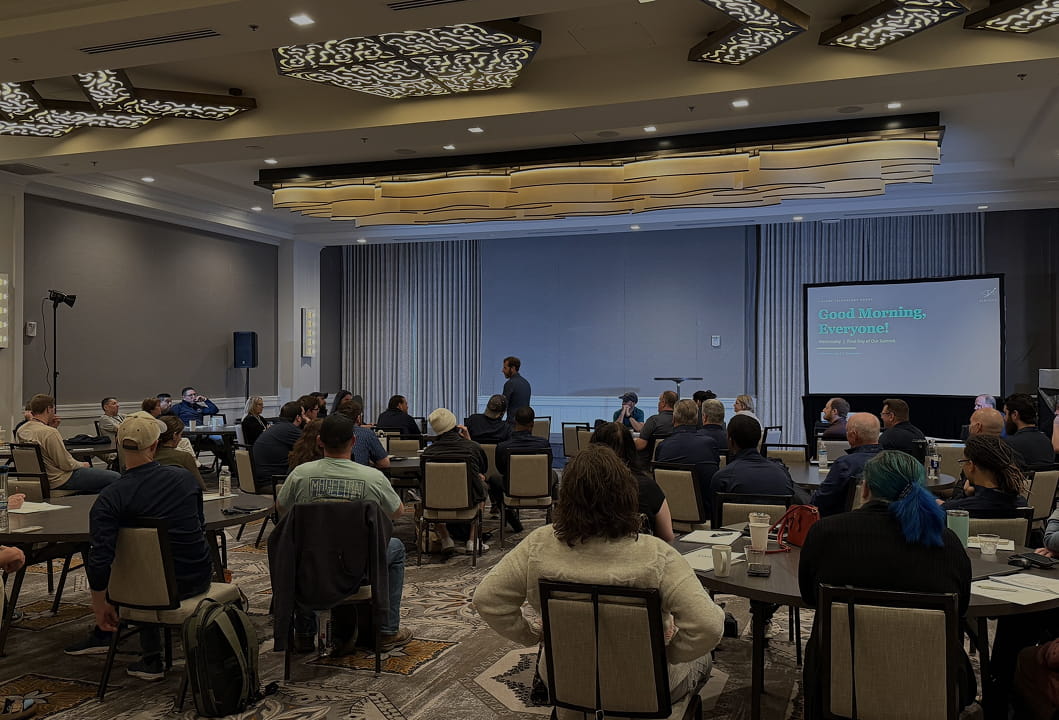 large training room with attendees, presentation screens, and ceiling lighting 
