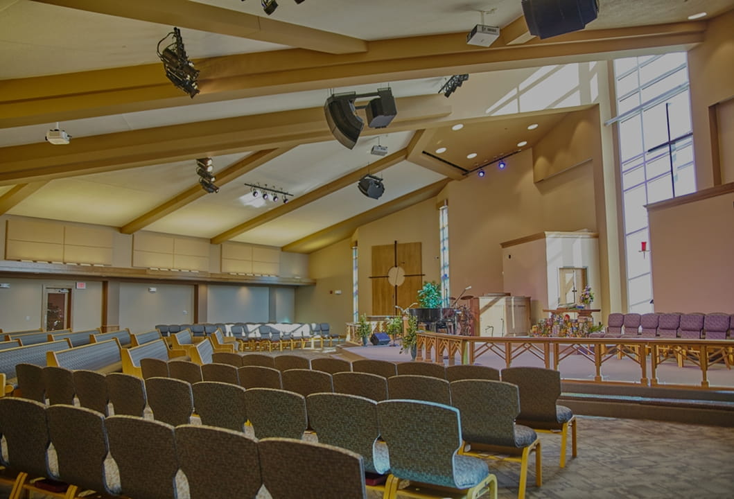 large worship space with seating, display screens, and platform lighting 