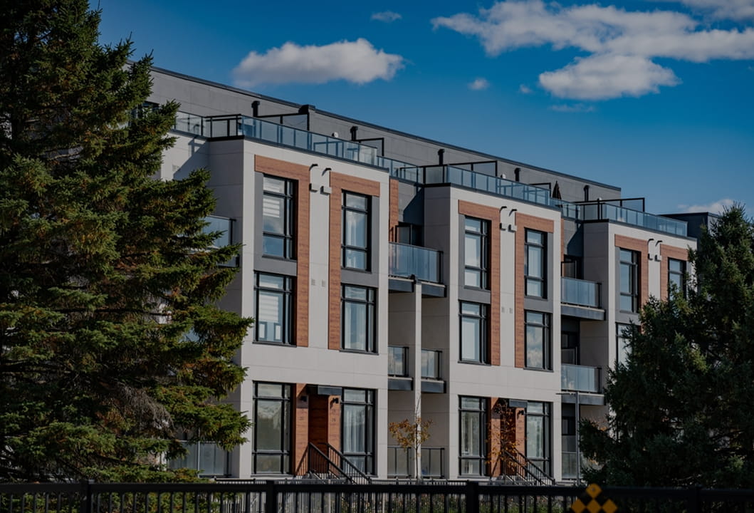 contemporary apartment community exterior with balconies, trees, and blue sky