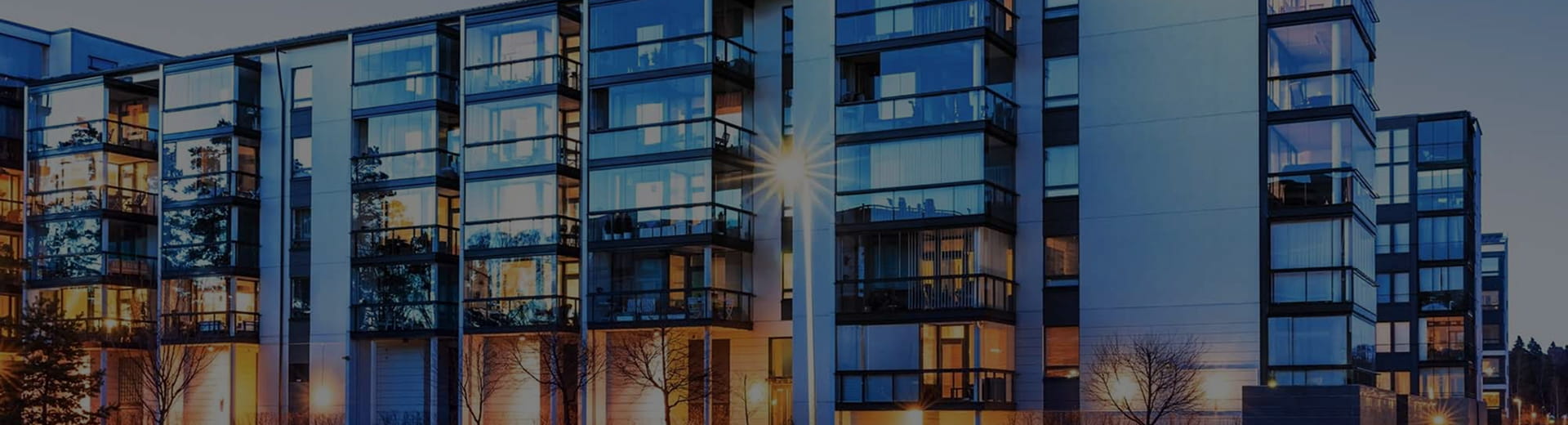 modern apartment building exterior with glass balconies at dusk